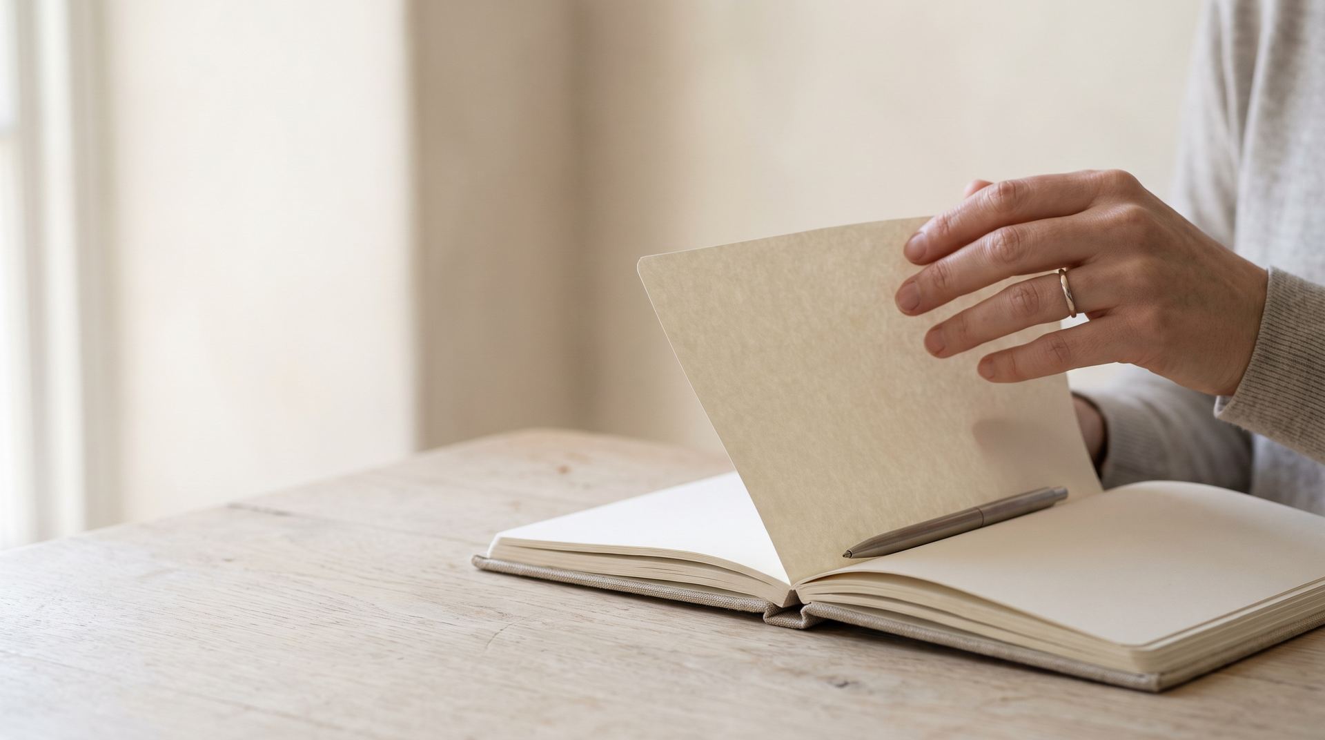 A hand turning a page of an open diary on an oak desk