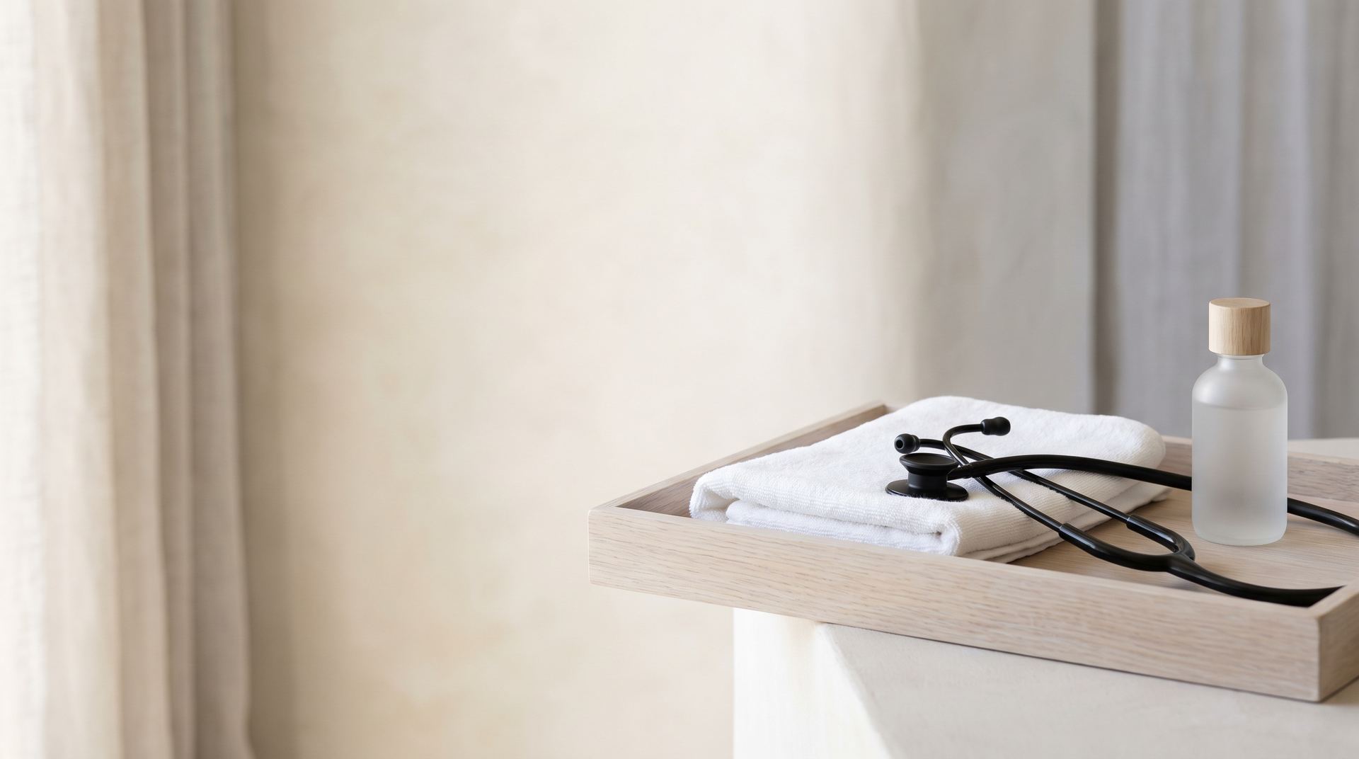 A tray with a folded towel, a stethoscope and a frosted glass bottle