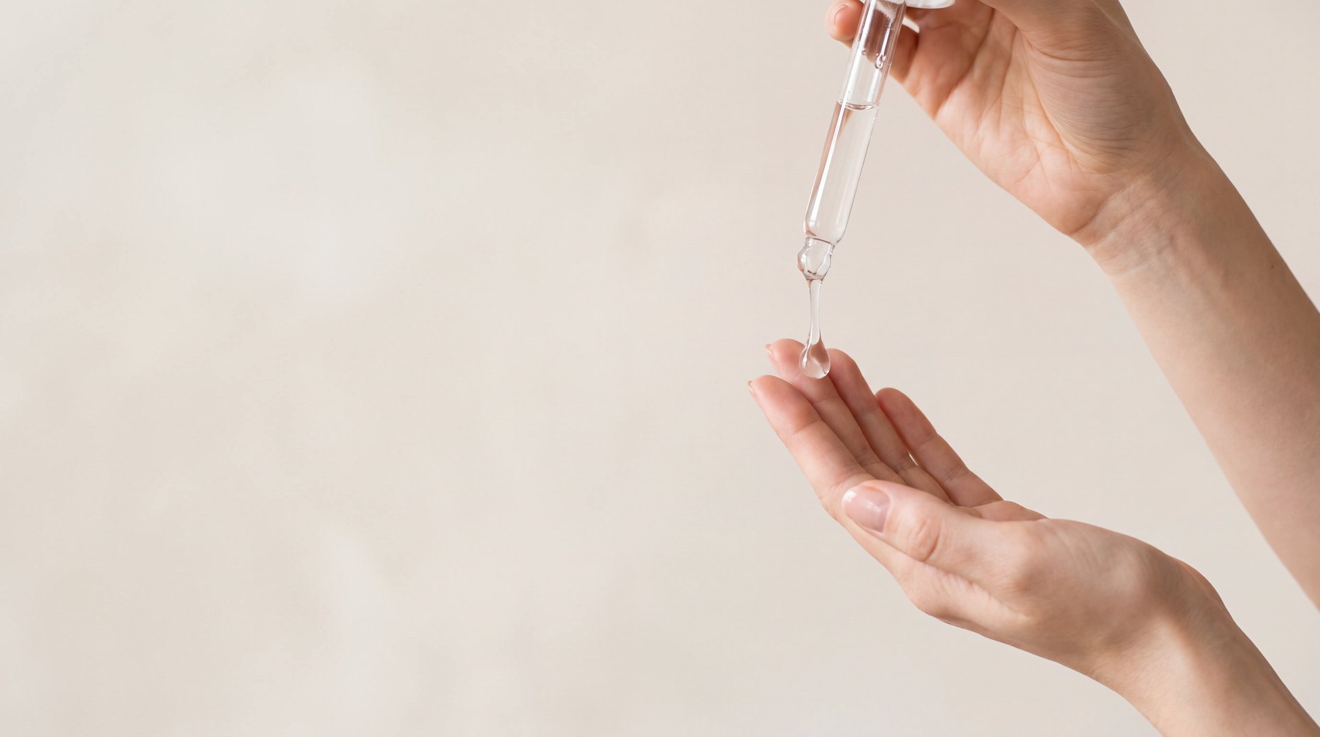 A drop of serum falling from a pipette onto a fingertip