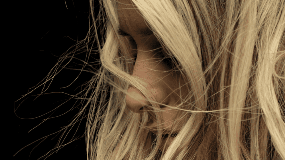A close-up of a person with long, blonde hair, partially obscuring their face against a dark background—a reminder of the transformative magic of hair rejuvenation at the Meyer Clinic. - Meyer Clinic
